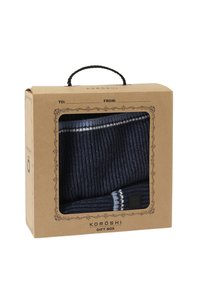 Set di sciarpa e cappello lavorati a maglia blu navy in una scatola regalo trasparente con carta kraft marrone e manico in corda nera. Include accenti a strisce bianche.
