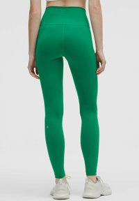 Högmidjade, enfärgade gröna leggings med ett mjukt, elastiskt tyg. Har en kroppsnära design och diskret logotypdetalj nära ankeln.