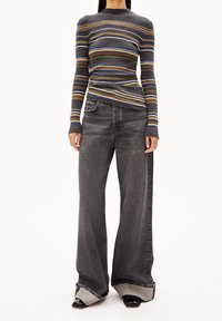 Top à manches longues en rib en bleu, gris et beige à rayures. Associé à un jean large gris avec des ourlets contrastés et des talons noirs.