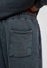 Koolgrijze sweatpants met een elastische tailleband, voorzien van een gestikt zakje aan de rechterkant en zacht, geweven stof.