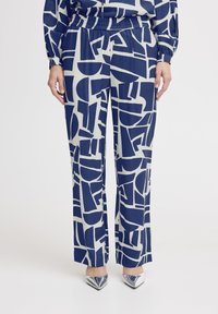 Marineblauwe en crèmekleurige gestreepte wijde broek met geometrische vormen, elastische tailleband en een gladde textuur. Gecombineerd met glanzende zilveren hakken.