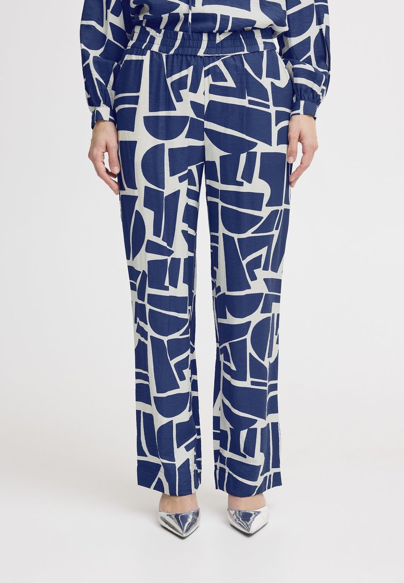 Marineblauwe en crèmekleurige gestreepte wijde broek met geometrische vormen, elastische tailleband en een gladde textuur. Gecombineerd met glanzende zilveren hakken.
