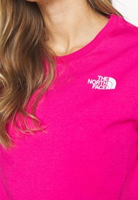 Fuchsia katoenen t-shirt met een ronde hals en korte mouwen; voorzien van een wit logo op de linkerkant van de borst.