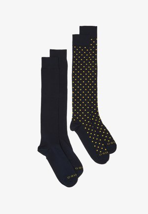 Two pairs of knee-high socks: one solid navy blue and the other navy with yellow polka dots. Both feature reinforced toe and ribbed top.