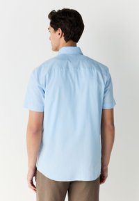 Kortærmet lyseblå skjorte med knapper lavet af bomuld, med en standardkrave og rygklap med en subtil struktur.