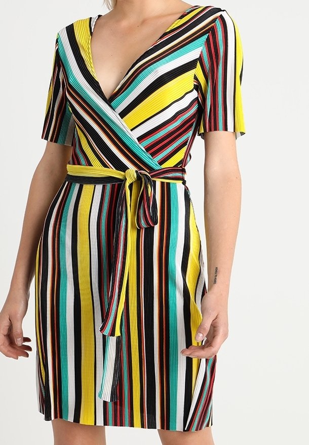 Femme portant une robe portefeuille à manches courtes avec des rayures verticales multicolores en jaune, noir, blanc, rouge et sarcelle, nouée à la taille.