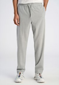 Ljust grå tapered-byxor med elastisk midja, i en strukturerad tygkvalitet och med sidfickor, kombinerat med vita sneakers.