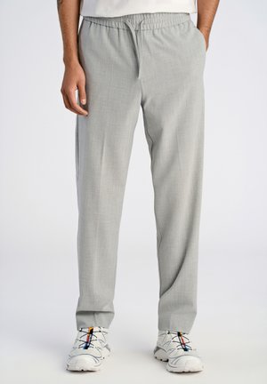 Ljust grå tapered-byxor med elastisk midja, i en strukturerad tygkvalitet och med sidfickor, kombinerat med vita sneakers.