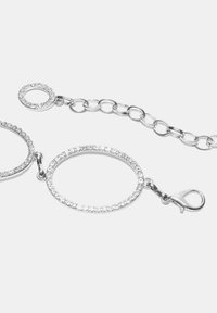 Stříbrný šperkový řetízek s kruhovými články, zdobený průhlednými krystaly a zapínáním na sponu. Hladký povrch s lesklým finišem.