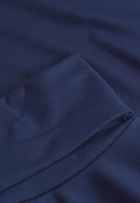 Tela azul marino con una textura suave, presenta un detalle de pliegue y bordes en capas, indicando un material suave y ligero.