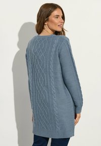 Hellblauem Pullover mit einem Strukturstrickmuster, der einen Rundhalsausschnitt und einen gerippten Saum aufweist. Lange Ärmel mit strukturierten Details an den Seiten.