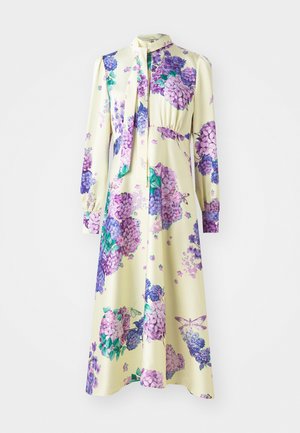 Langärmliges Kleid aus glattem Stoff, mit gelbem Grund und lila Blumenmustern. Es hat einen gebundenen Ausschnitt und eine geraffte Taille.
