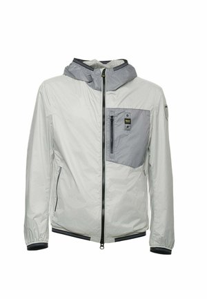 Giacca leggera e impermeabile di colore grigio chiaro con tasca a pannello grigia, chiusura con zip e polsini elasticizzati. Presenta un cappuccio e tasche laterali.