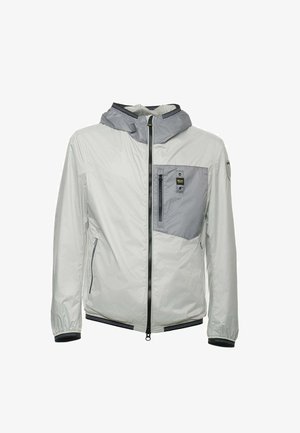 Lichte, waterdichte jas in lichtgrijs met een grijze paneelzak, ritssluiting en elastische manchetten. Voorzien van een capuchon en zijzakken.