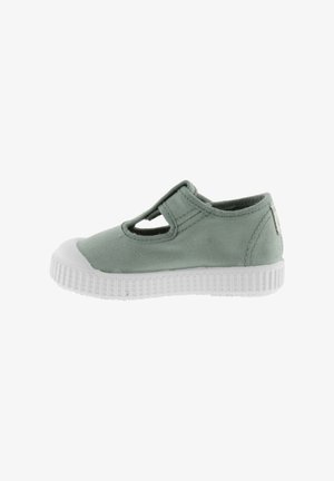 Zapato de lona verde con puntera y suela de goma blanca, que presenta un diseño perforado en la parte superior y detalles cosidos a lo largo de las costuras.