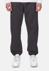 Dark gray sweatpants with elastic cuffs, featuring a subtle logo detail. Made from soft fabric, designed for a relaxed fit.