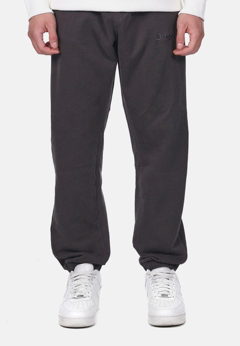 Dark gray sweatpants with elastic cuffs, featuring a subtle logo detail. Made from soft fabric, designed for a relaxed fit.