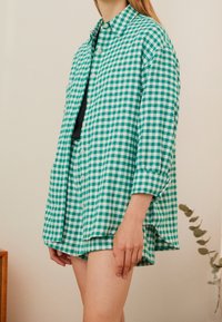 Green and white gingham shirt, featuring a button-up front, long sleeves, and a loose fit, paired with matching shorts.
