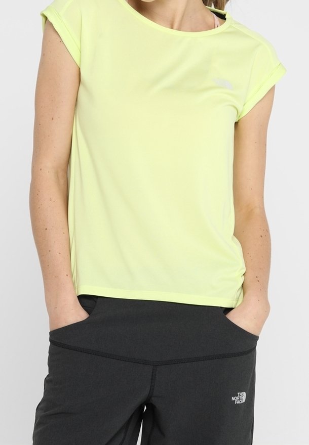 Lichtgele sporttop gemaakt van vochtregulerende stof, met korte mouwen en een ronde hals, gecombineerd met donkergrijze broek.