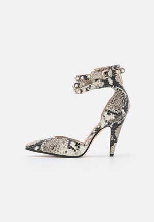 High-heeled pump with a pointed toe, black and white snake print, ankle strap with decorative buttons, textured surface, and stiletto heel.