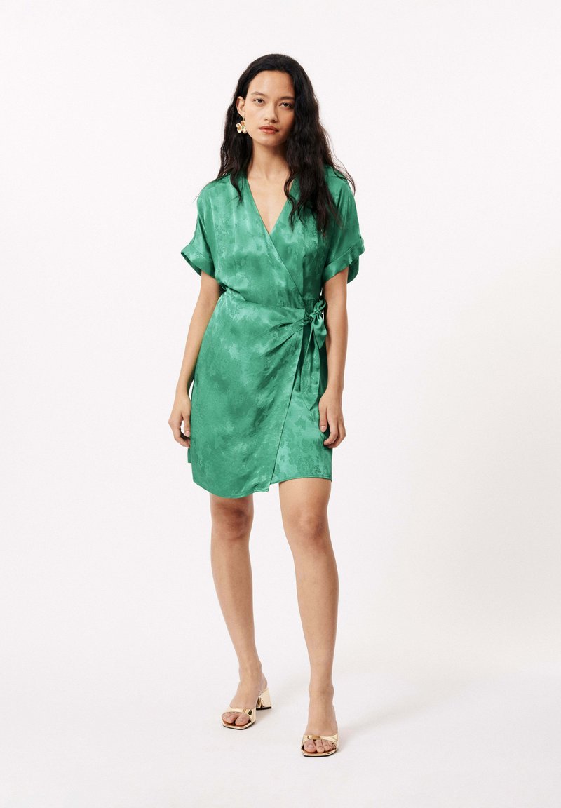 Robe portefeuille verte en satin léger, à manches kimono courtes, cintrée à la taille avec un nœud, présente un motif floral subtil et un décolleté en V.