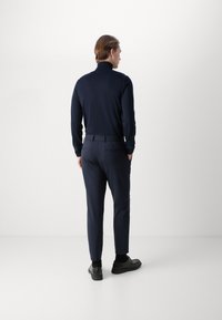 Σκούρο μπλε ζιβάγκο και αντίστοιχο παντελόνι από μαλακό ύφασμα. Το παντελόνι διαθέτει ελαστική μέση και κομψά μαύρα παπούτσια.