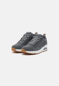 Gray sports shoes featuring a suede and synthetic upper, white midsole, gum rubber outsole, and prominent lacing with a rear pull tab.