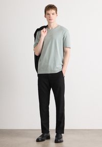 Light green short-sleeve t-shirt with a relaxed fit, paired with black trousers and black shoes. Simple, unembellished design.