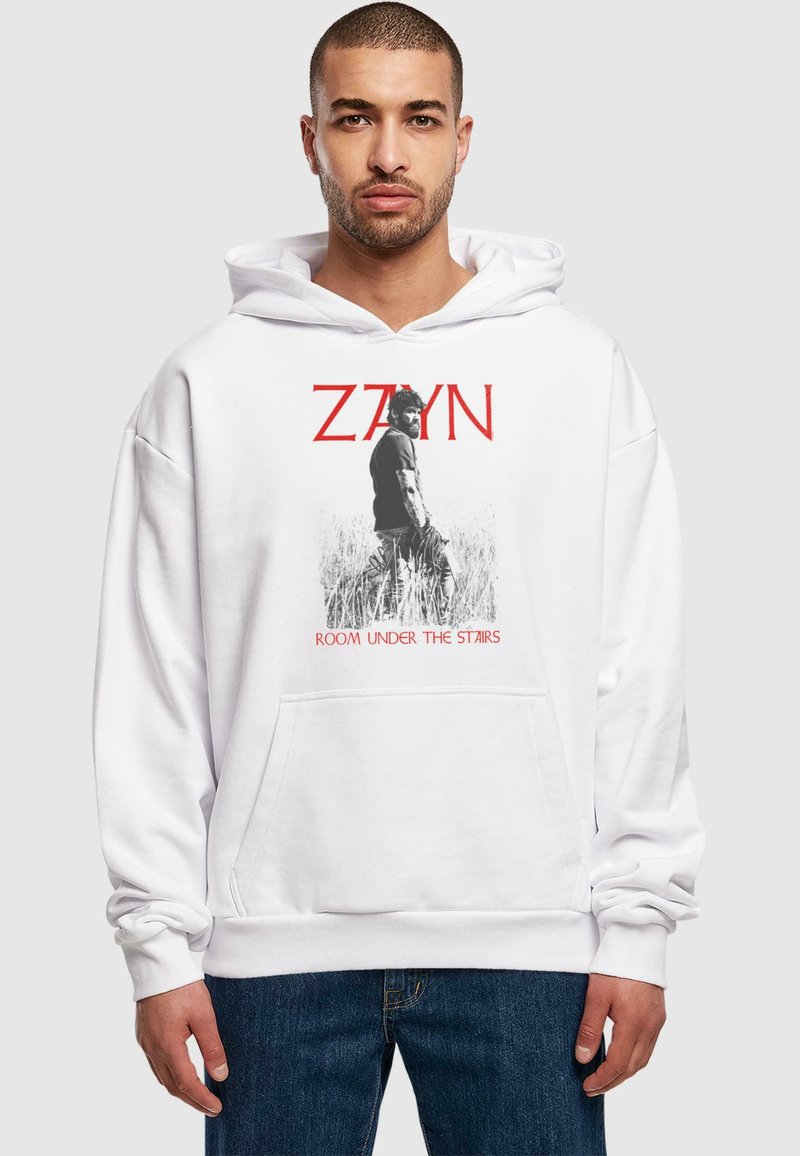 Felpa bianca con cappuccio caratterizzata da una stampa grafica di un uomo in bianco e nero, con testo rosso che recita "ZAYN" e "ROOM UNDER THE STAIRS." Design con tasca frontale.