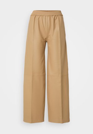 Pantalons larges en simili cuir beige avec une taille élastique et des coutures verticales, présentant une texture lisse et mate.