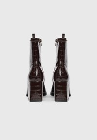 Botas de tobillo de imitación de cuero marrón con textura de cocodrilo brillante, tacones cuadrados y cierre de cremallera en la parte posterior.