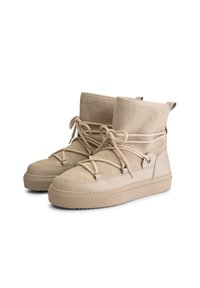 Beige suede ankle boots with thick textured rubber soles and rope-style laces wrapped around the upper part for a secure fit.