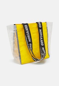 Borsa tote trasparente con interno giallo, manici neri con testo "Nørgaard", forma rettangolare, texture liscia e bordi rinforzati.