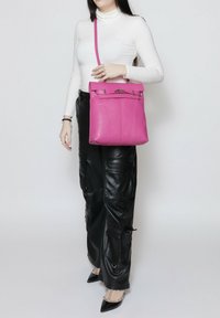 Roze leren handtas met een gestructureerde vorm, bovenste sluiting, zilverkleurige hardwareaccenten en een lange verstelbare schouderband voor crossbody draagstijl.