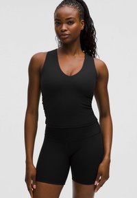 Zwarte sportieve tanktop met een V-hals en ribbelstructuur, gecombineerd met bijpassende hoge shorts. Beide zijn aansluitend en naadloos.
