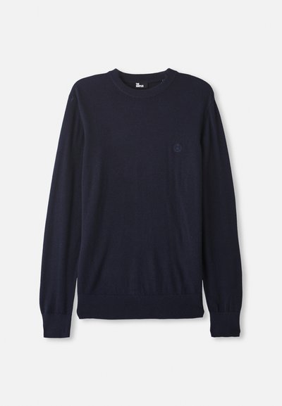 Navy blue knit sweater with long sleeves, crew neck, ribbed cuffs, and waist, featuring a small, subtle logo on the chest.