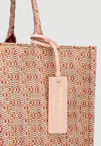 Geweven schoudertas in pasteltinten van roze, oranje en crème, met een roze leren label dat "Coccinelle Nice Weekender Bag" is geperst.