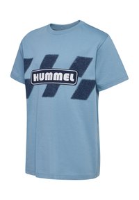 Lyseblå bomuld t-shirt med et struktureret marineblåt chevron-design og et centralt "HUMMEL" logo i en kontrasterende hvid rektangulær boks.