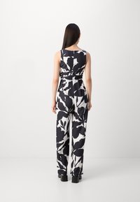 Monos de flores en blanco y negro con un diseño sin mangas, cintura ajustada y pantalones de pierna ancha. Tejido suave y ajuste relajado.