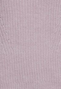 Hellrosa gestrickter Stoff mit einem strukturierten Muster und geripptem Saum. Das Strickmaterial ist weich und leicht flauschig, was ein lockeres, luftiges Design zur Geltung bringt.