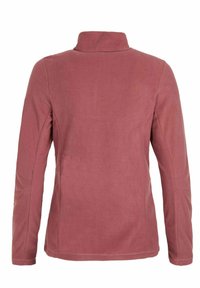 Set bagfra af en ensfarvet støvet rosa fleecejakke med lange ærmer og en opretstående krave.