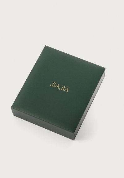 Πράσινο ορθογώνιο κουτί με γυαλιστερή επιφάνεια, με χρυσά γράμματα "JLA JIA" κεντραρισμένα �στην επάνω επιφάνεια. Επίπεδο σχέδιο, χωρίς επιπλέον μοτίβα.