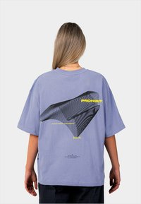 Fialové nadměrné tričko s černým grafickým designem a žlutým textem na zádech, zdobené vlnkovými vzory a různými štítky.