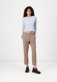 Haut à manches longues bleu clair à côtes avec un ourlet festonné, associé à un pantalon beige fuselé et des mocassins noirs épais.