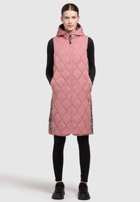 Gequiltete rosa Weste mit Kapuze, ausgestattet mit Seitentaschen und kontrastierenden schwarzen Seitenstreifen mit Text. Hergestellt aus leichtem, gepolstertem Material.