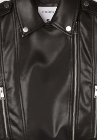 Giacca da moto nera in pelle artificiale con accessori in argento, tasche con zip e spalline, caratterizzata da una superficie liscia e testurizzata.