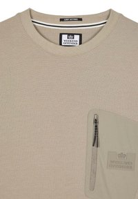 Beige sweatshirt med rund hals, der har en lynlåslomme på brystet og et vævet mærke, der viser "WEEKEND OFFENDER" og et krone-logo.