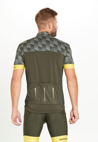 Maillot de cyclisme en olive foncé avec un motif à carreaux, accents jaunes sur les manches et un design de poche arrière avec des détails réfléchissants.