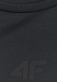 Gros plan sur un tissu noir avec un logo 4F en relief de couleur gris foncé sur la partie inférieure.
