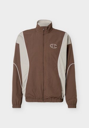 Giacca con zip marrone e grigio chiaro, collo alto, polsini elastici, orlo elasticizzato, piping bianco e piccolo logo sul petto sinistro.